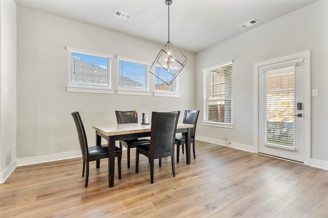 dining room with light wood-style flooring, plenty of natural light, baseboards, and a chandelier