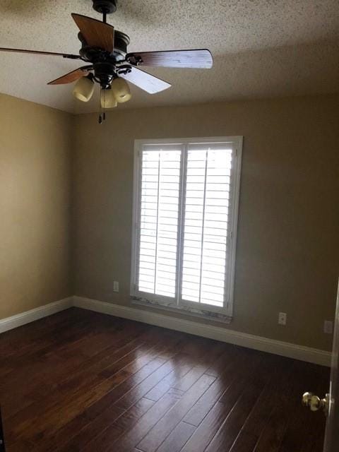 unfurnished room with healthy amount of natural light, baseboards, ceiling fan, dark wood-style flooring, and a textured ceiling