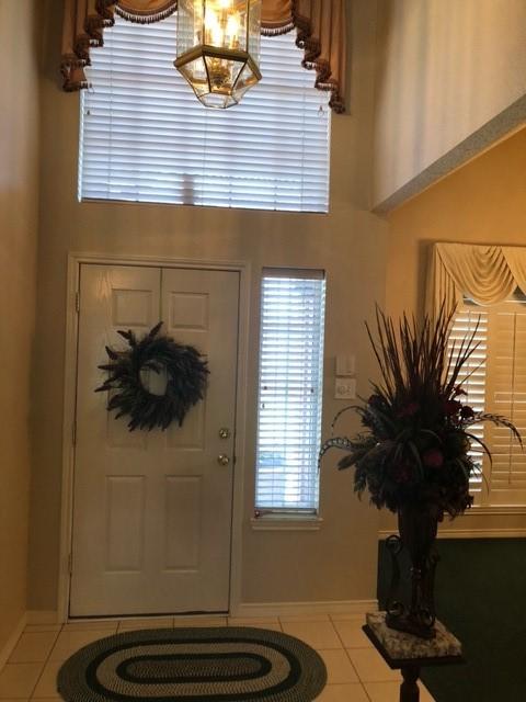 tiled entryway with baseboards and a towering ceiling