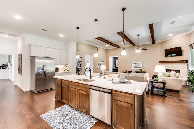 kitchen with appliances with stainless steel finishes, a sink, a ceiling fan, beamed ceiling, and an island with sink