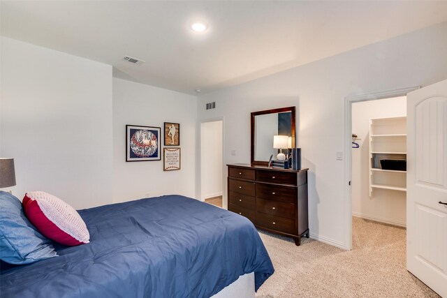 bedroom featuring light colored carpet, a walk in closet, and baseboards