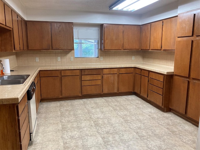 12735 County Road 2922, Eustace, TX 75124 - kitchen featuring a sink, brown cabinetry, backsplash, and light floors