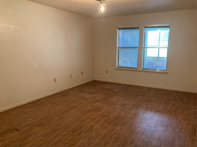 12735 County Road 2922, Eustace, TX 75124 - spare room featuring a textured ceiling, dark wood-style floors, and baseboards