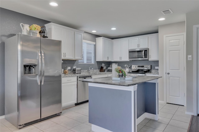 2208 Heaton St, Forney, TX 75126 - kitchen with appliances with stainless steel finishes, white cabinetry, light tile patterned flooring, a kitchen island, and light stone countertops