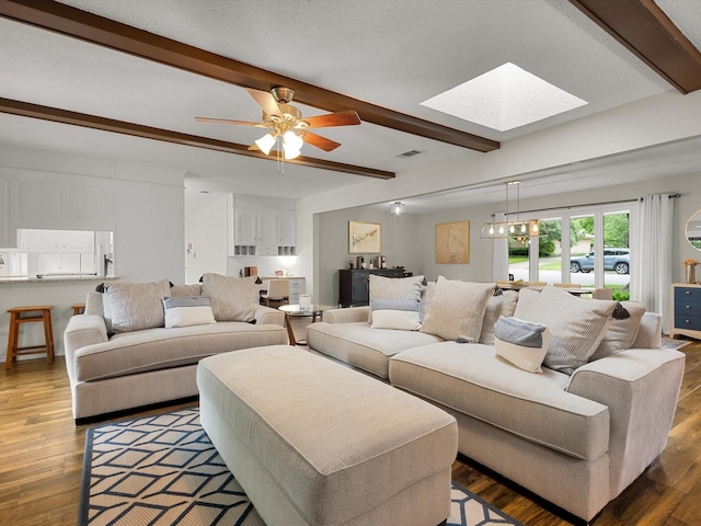 living room with beamed ceiling, a skylight, wood finished floors, and ceiling fan