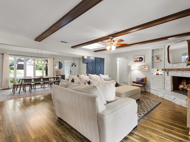 living area with dark wood-style flooring, beamed ceiling, a ceiling fan, and a premium fireplace