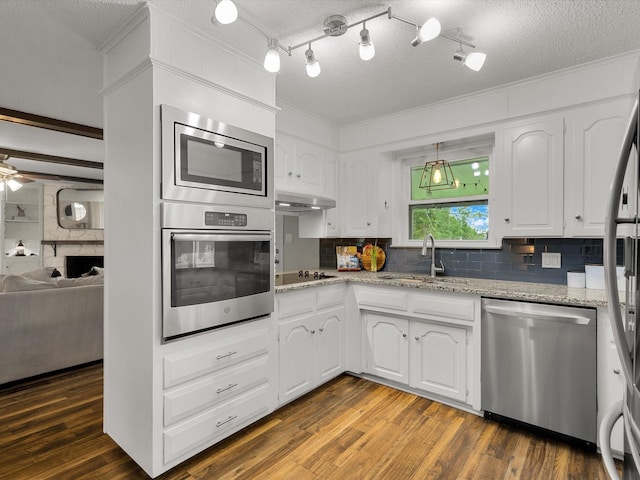 kitchen with stainless steel appliances, a sink, tasteful backsplash, white cabinetry, and light stone counters