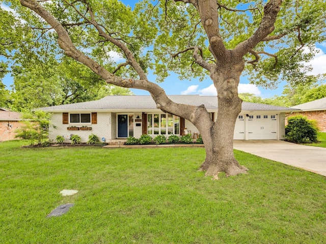view of front of house with driveway, brick siding, a garage, and a front yard