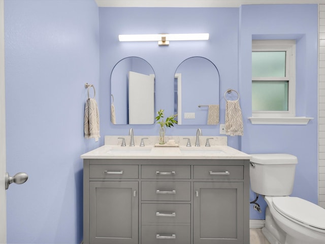 bathroom with toilet and double vanity