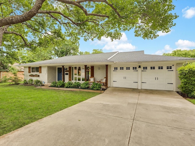 ranch-style home featuring a garage, driveway, brick siding, a front yard, and roof with shingles