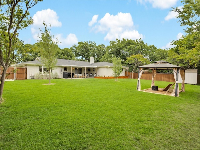 rear view of house with a gazebo, a patio, a chimney, and brick siding