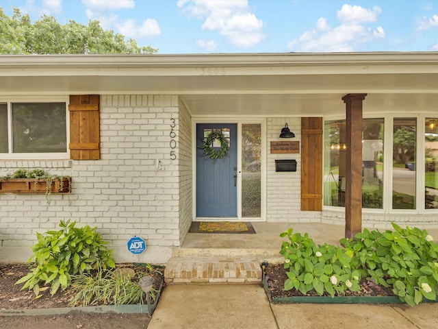 entrance to property featuring brick siding and a porch