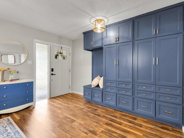 mudroom with dark wood-style flooring, baseboards, and a textured ceiling