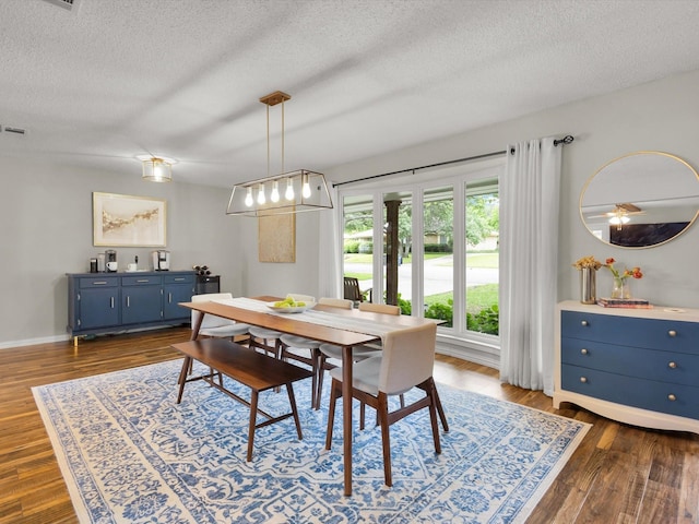 dining area with a textured ceiling, dark wood-type flooring, and baseboards