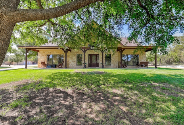 back of property with stone siding and a lawn