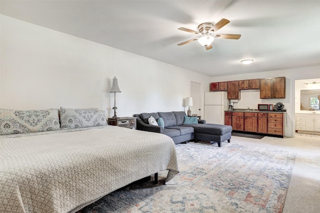 bedroom featuring freestanding refrigerator, light carpet, a sink, connected bathroom, and ceiling fan