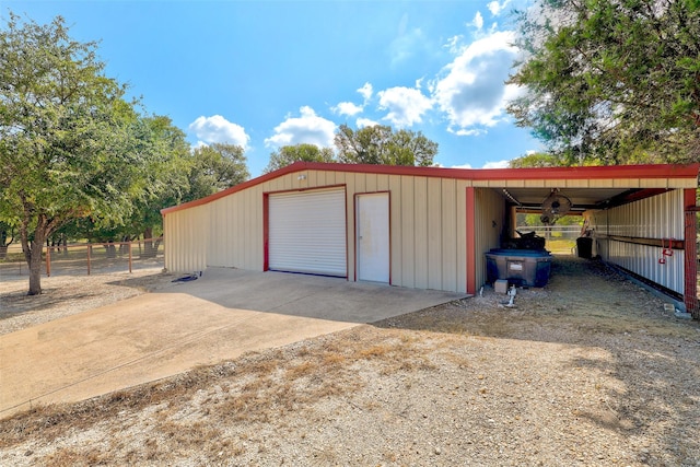 garage with driveway, fence, and a garage