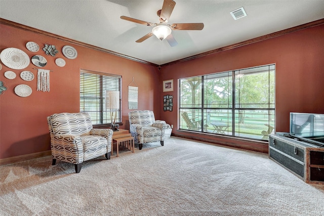living area featuring carpet flooring, crown molding, plenty of natural light, and a ceiling fan