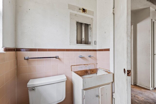 64 Pershing Dr Unit A & B, Denison, TX 75020 - bathroom with toilet, tile walls, wainscoting, and wood finished floors