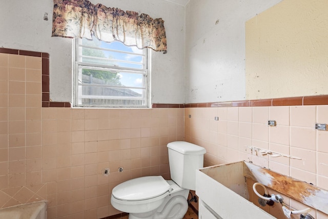 64 Pershing Dr Unit A & B, Denison, TX 75020 - bathroom featuring tile walls, toilet, and a wainscoted wall