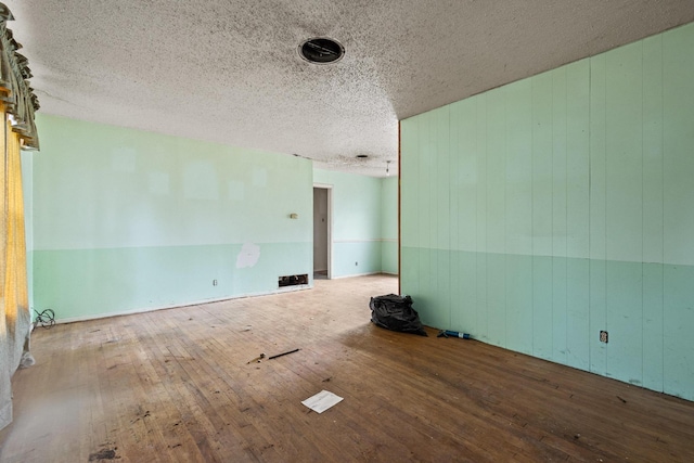 64 Pershing Dr Unit A & B, Denison, TX 75020 - unfurnished room featuring hardwood / wood-style flooring, a textured ceiling, and wooden walls