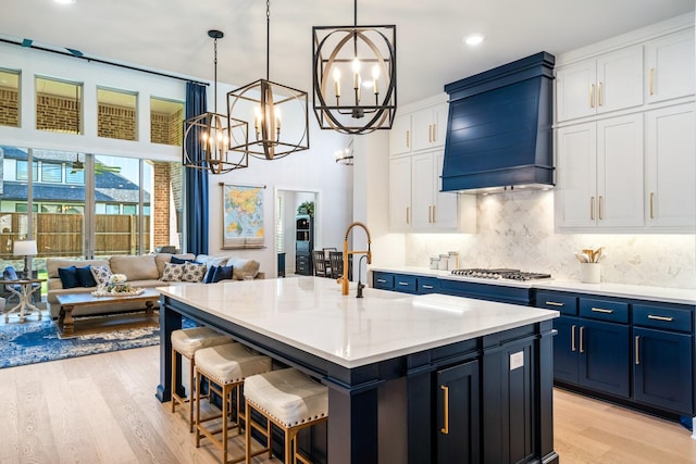 2200 Sandalwood Dr, Prosper, TX 75078 - kitchen featuring a chandelier, light wood-style flooring, blue cabinetry, premium range hood, and open floor plan