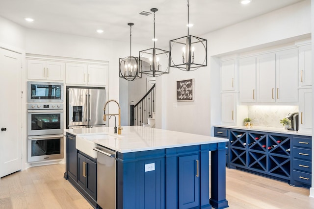 2200 Sandalwood Dr, Prosper, TX 75078 - kitchen featuring appliances with stainless steel finishes, blue cabinetry, light wood finished floors, a sink, and recessed lighting