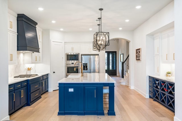 2200 Sandalwood Dr, Prosper, TX 75078 - kitchen featuring appliances with stainless steel finishes, custom range hood, arched walkways, light countertops, and light wood-type flooring