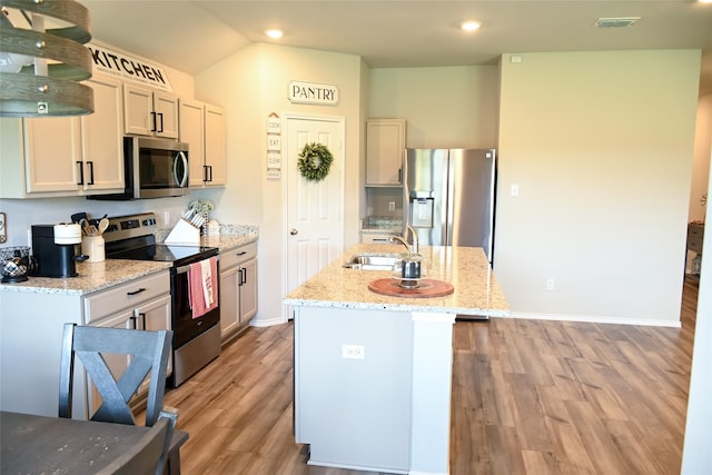 7121 Guadalupe Rd, Waco, TX 76633 - kitchen with stainless steel appliances, a sink, light wood-style floors, light stone countertops, and a kitchen island with sink
