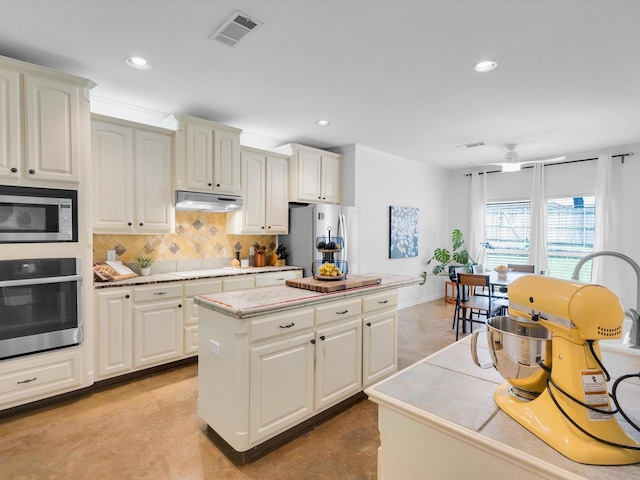 1806 Briarcrest Ln, Arlington, TX 76012 - kitchen with stainless steel appliances, a kitchen island, tasteful backsplash, under cabinet range hood, and recessed lighting