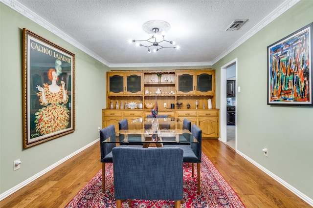 109 Tuscany Ct, Irving, TX 75062 - dining area featuring light wood-style flooring, a textured ceiling, ornamental molding, and a chandelier