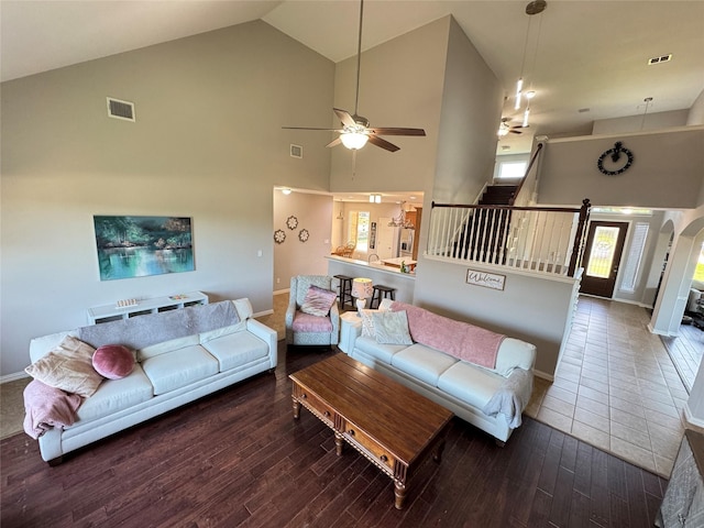 living room with a ceiling fan, high vaulted ceiling, wood finished floors, baseboards, and arched walkways