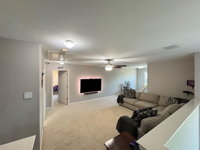 living room with attic access, light colored carpet, ceiling fan, and baseboards
