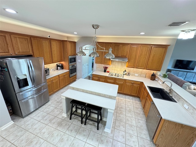 kitchen with appliances with stainless steel finishes, a sink, brown cabinets, decorative backsplash, and light countertops