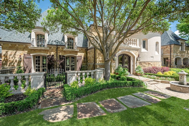6168 Beverly Dr, Frisco, TX 75034 - french country style house with stone siding, french doors, a gate, and fence
