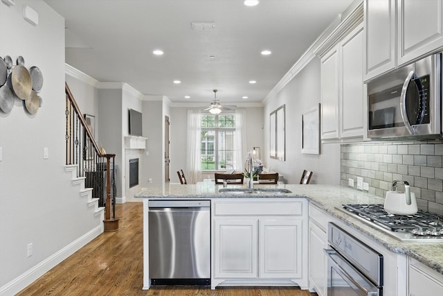 829 Milton Way, Coppell, TX 75019 - kitchen with stainless steel appliances, a sink, a peninsula, white cabinets, and recessed lighting