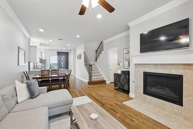829 Milton Way, Coppell, TX 75019 - living room with wood finished floors, crown molding, stairs, ceiling fan, and a tiled fireplace