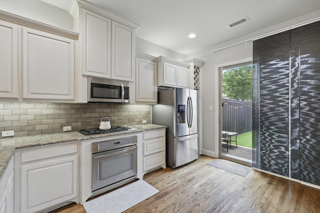829 Milton Way, Coppell, TX 75019 - kitchen featuring stainless steel appliances, light wood-style floors, backsplash, light stone counters, and white cabinets