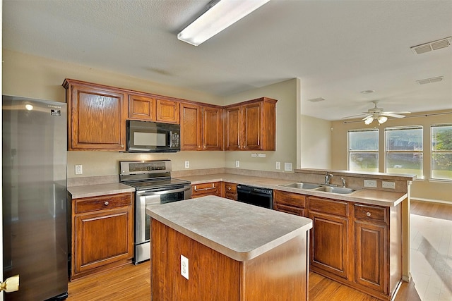 6917 Tessla Dr, Dallas, TX 75241 - kitchen featuring black appliances, a sink, light wood finished floors, a peninsula, and light countertops