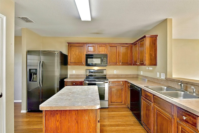 6917 Tessla Dr, Dallas, TX 75241 - kitchen featuring black appliances, a sink, light wood finished floors, light countertops, and a kitchen island