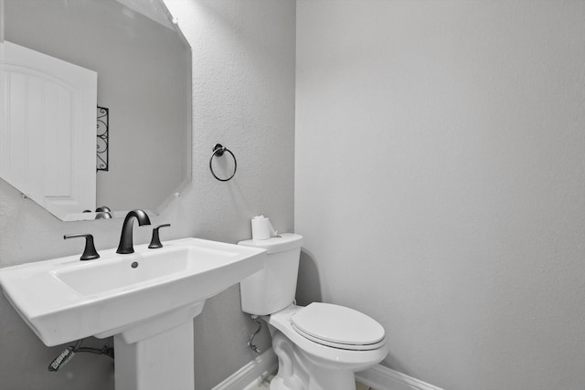 10825 Thorngrove Ct, Fort Worth, TX 76052 - bathroom with baseboards, toilet, a sink, and a textured wall