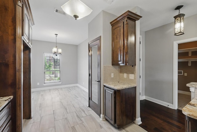 10825 Thorngrove Ct, Fort Worth, TX 76052 - kitchen with a chandelier, backsplash, light stone counters, hanging light fixtures, and dark brown cabinetry