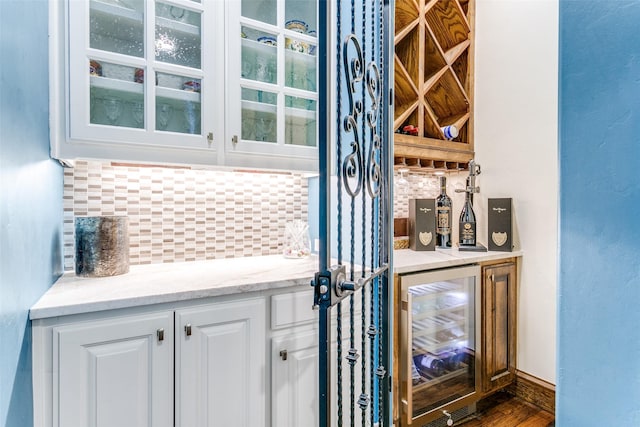 indoor dry bar with beverage cooler, backsplash, and wood finished floors