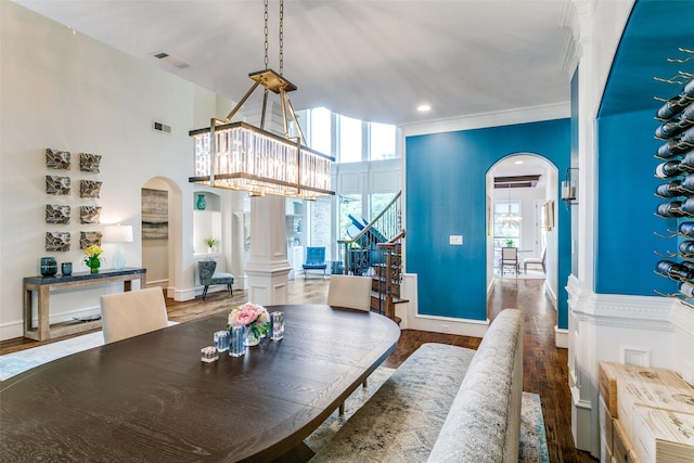 dining space featuring arched walkways, stairway, wood finished floors, and ornamental molding