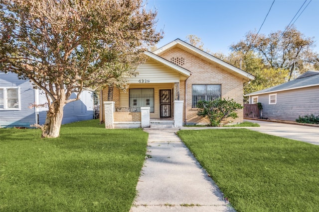 view of front of home with covered porch, brick siding, and a front lawn