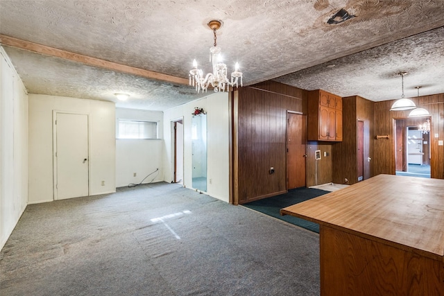 kitchen featuring a textured ceiling, a chandelier, wood walls, carpet floors, and brown cabinets