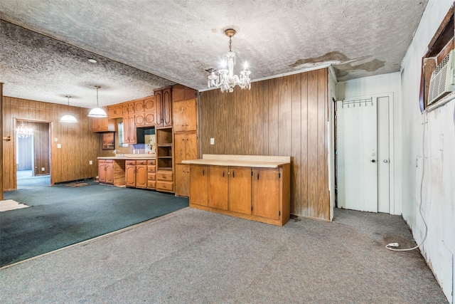 kitchen featuring brown cabinets, carpet flooring, wood walls, a chandelier, and a textured ceiling