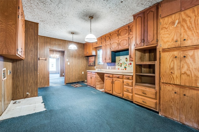 kitchen featuring dark carpet, brown cabinetry, wood walls, light countertops, and a textured ceiling
