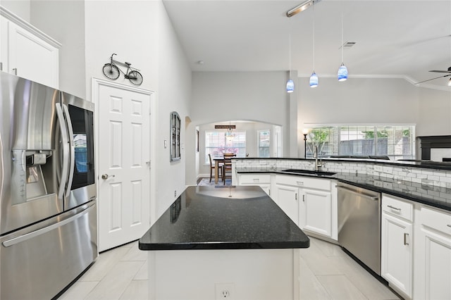 kitchen with appliances with stainless steel finishes, arched walkways, light tile patterned floors, a ceiling fan, and a sink