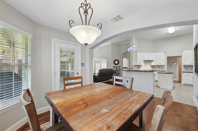 dining space featuring arched walkways, light wood-style floors, and baseboards
